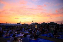 夕日の中祭りを楽しむ人たちの写真